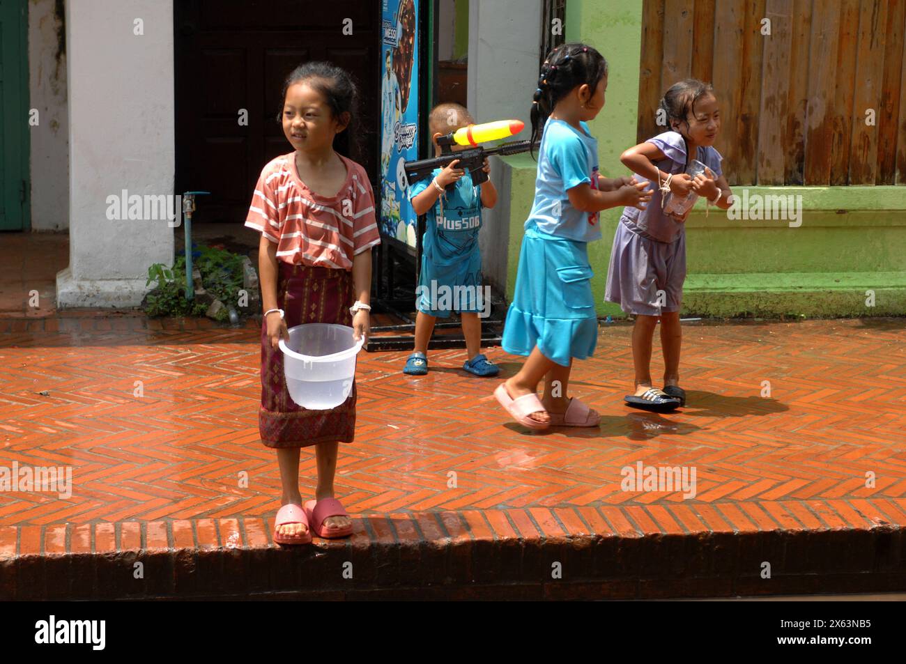 Bambini pronti a gettare acqua alla parata di Pi mai come parte delle celebrazioni di Capodanno a Luang Prabang, Laos, Foto Stock