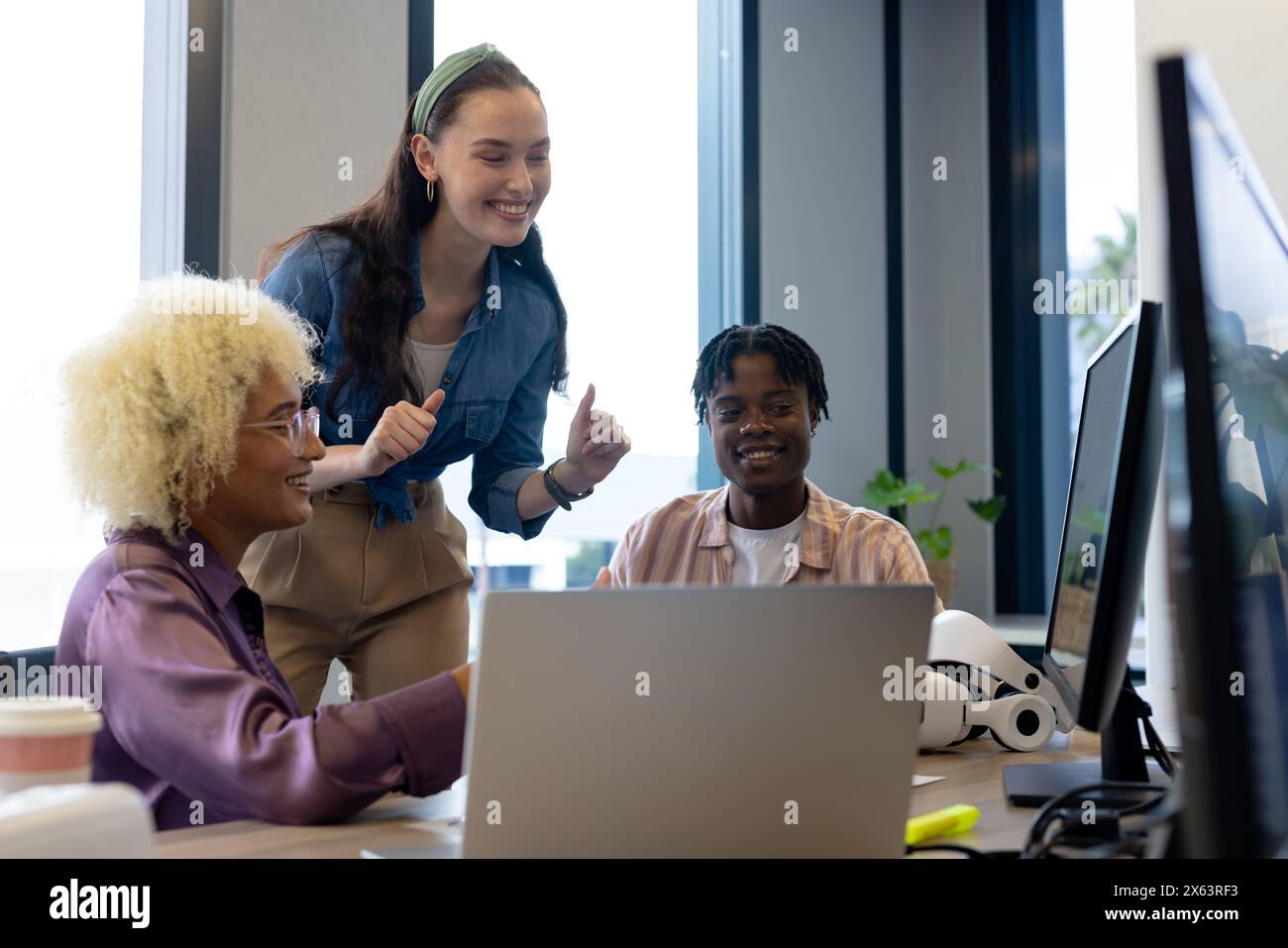 In un ufficio moderno, giovani e eterogenei che condividono idee al computer Foto Stock