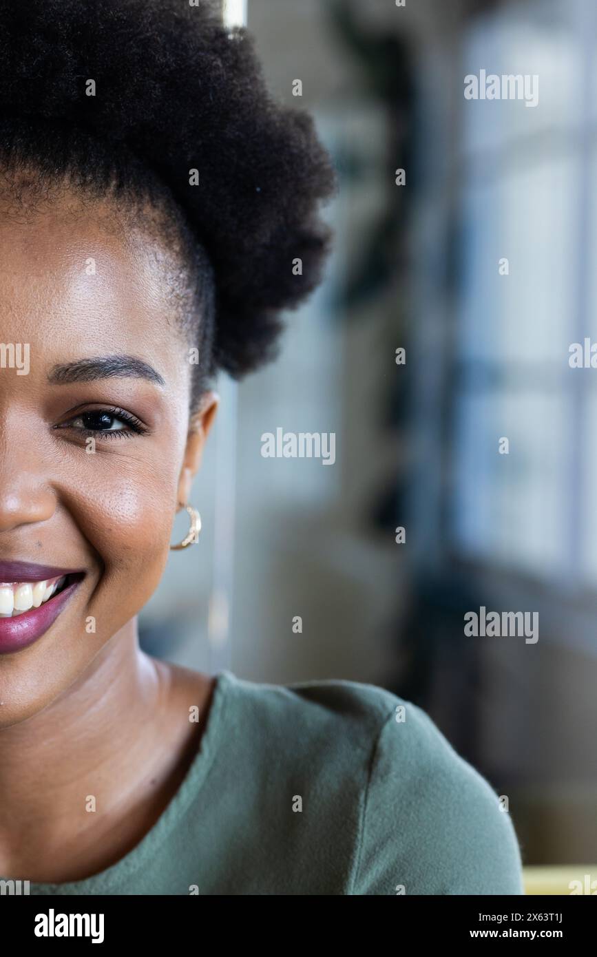 In ufficio, donna d'affari afro-americana sorridente, indossa la parte superiore verde, copia spazio Foto Stock