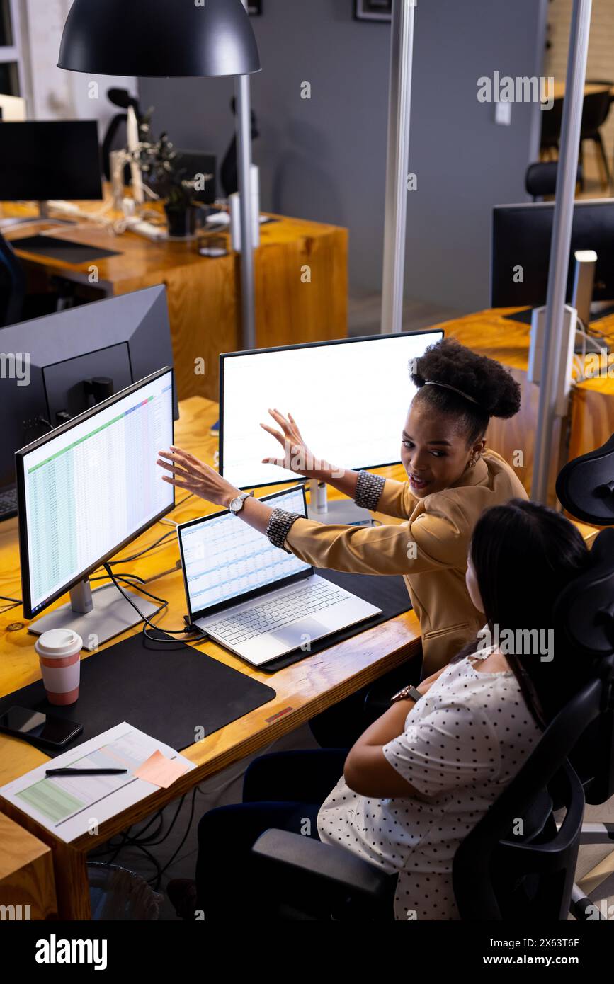 Diverse colleghe che discutono di dati, lavorano fino a tardi Foto Stock