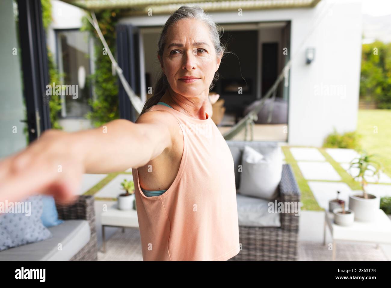 A casa, donna caucasica matura che fa yoga nel suo cortile Foto Stock