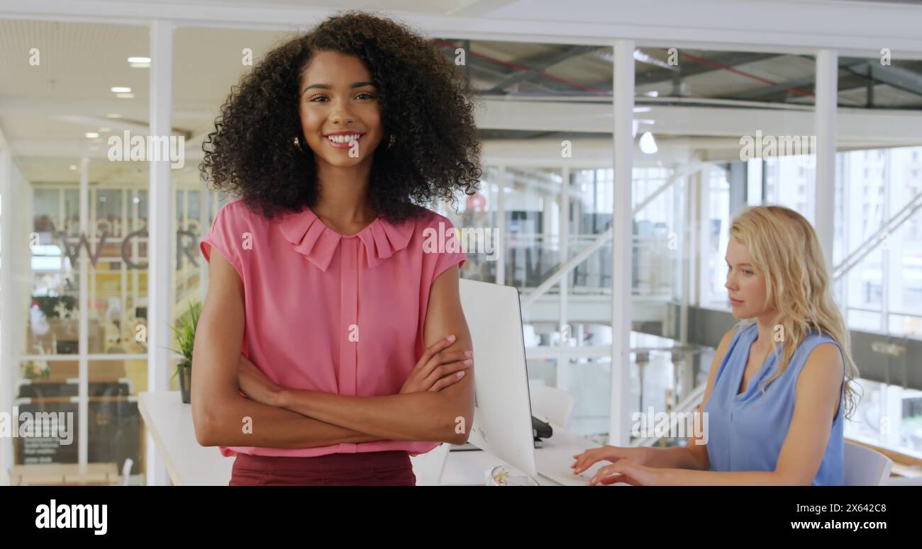 Immagine di un collega birazziale in piedi, collega caucasico che usa il computer Foto Stock