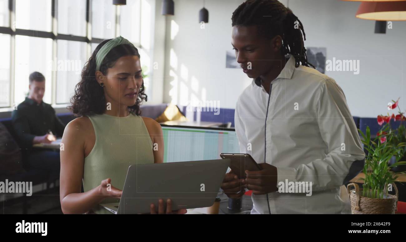 Immagine di donna birazziale con laptop parla lavorare con l'uomo afroamericano su smartphone Foto Stock