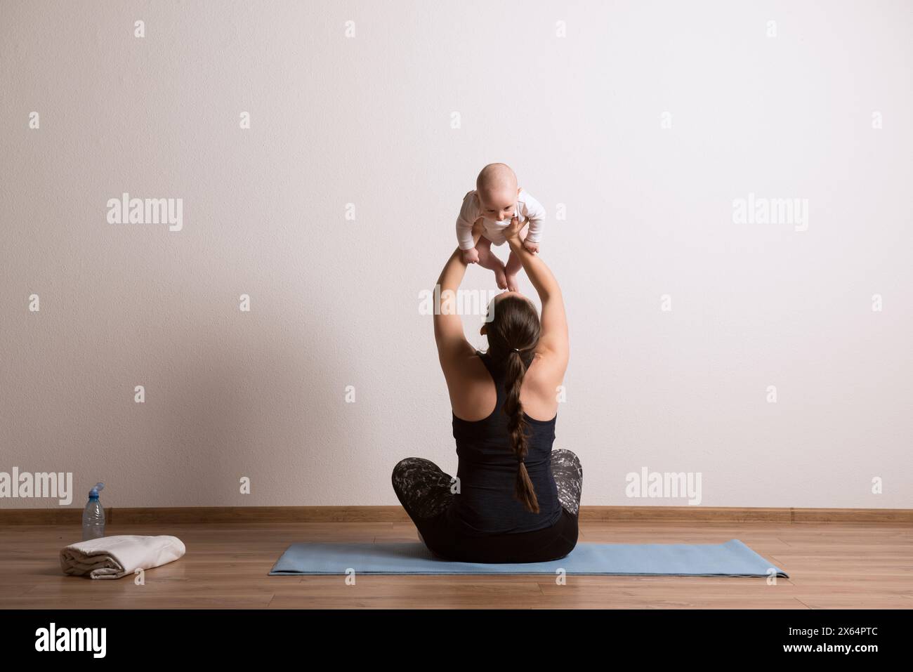 Esercizio domestico per mamma e bambino, mamma e me. Attività fisica per la madre durante il legame con i bambini. Foto Stock