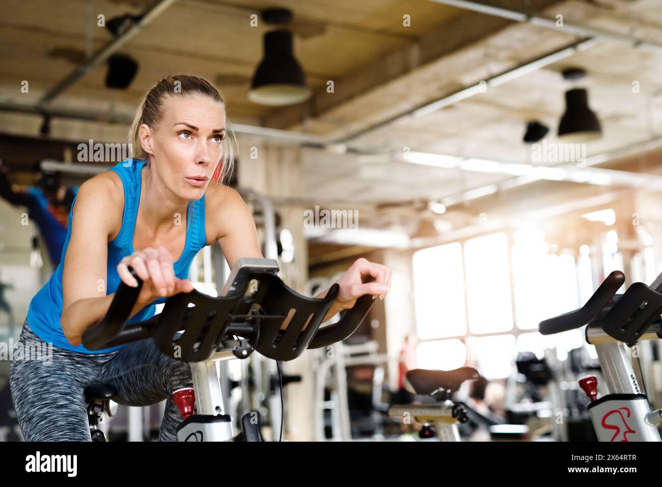 Bella donna sportiva in bicicletta con cyclette in palestra. Allenamento di routine per la salute fisica e mentale della donna Foto Stock