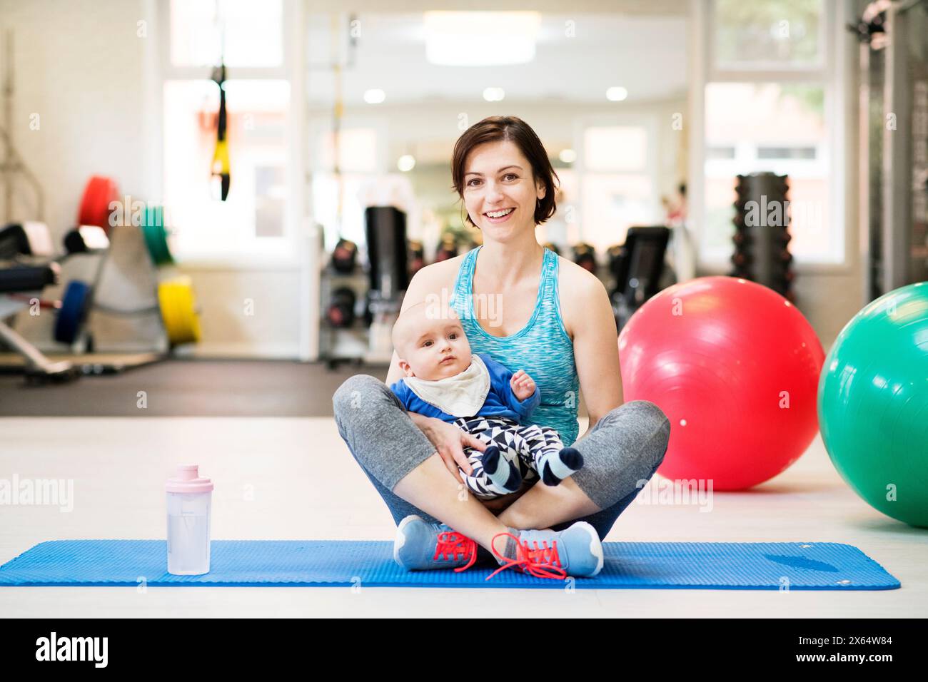 Ritratto di una nuova mamma in una lezione di gruppo in palestra. Le mamme rimangono attive mentre si nutrono con i bambini. Lezione di movimento del bambino. Foto Stock