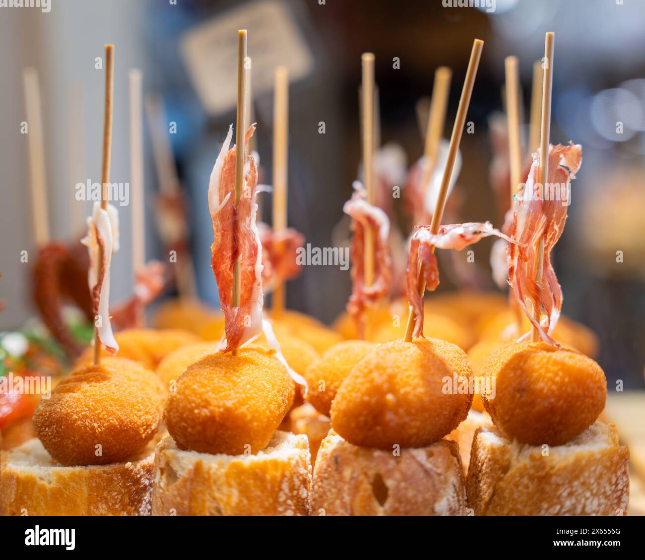 Pinchos baschi (una forma di tapas spagnole), con pane e prosciutto spagnolo, in un bar. Spuntino tipico dei Paesi Baschi, pinchos o spiedini di pinxtos Foto Stock