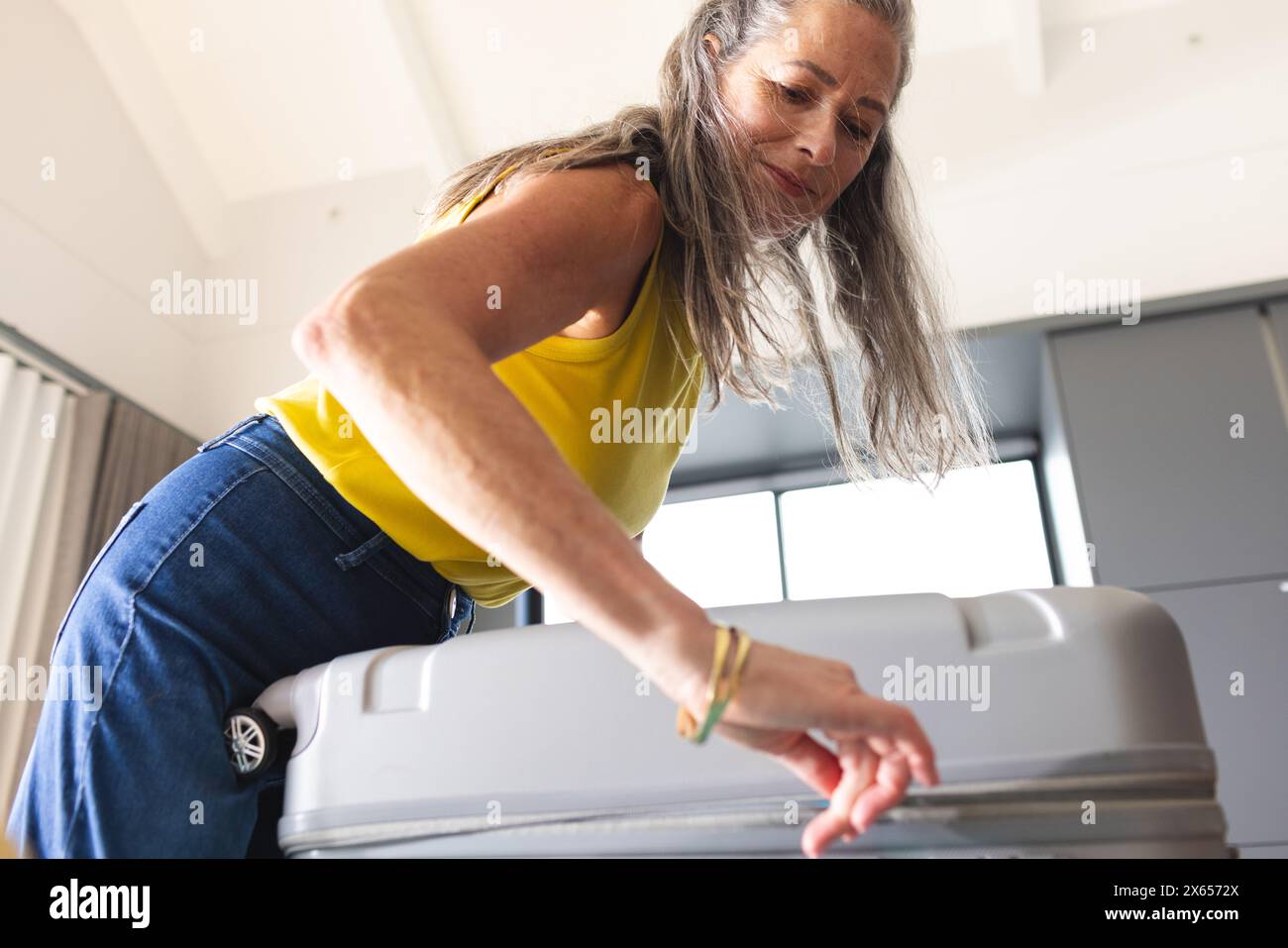 A casa, donna matura caucasica che apre la valigia Foto Stock