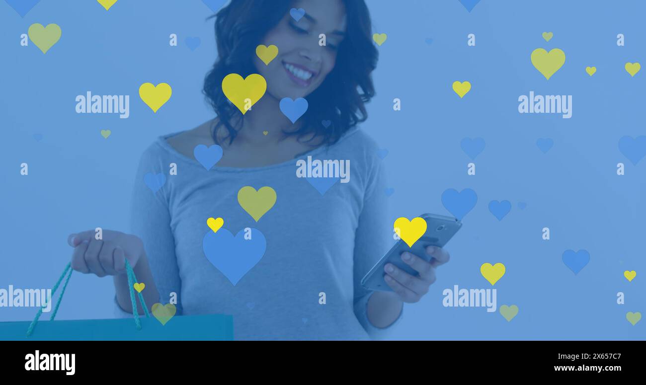 Una giovane donna con i capelli scuri tiene in mano la borsa della spesa e guarda il suo smartphone Foto Stock