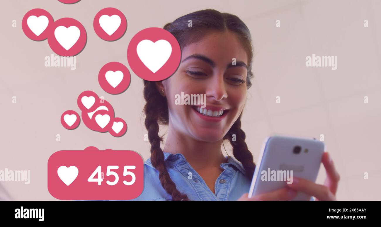 Più icone cardiache con numeri sempre più numerosi che fluttuano contro il caucasico utilizzando lo smartphone Foto Stock