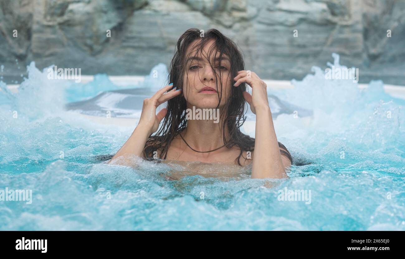 ritratto di una donna bagnata sexy e sensualmente seducente in acque turchesi e spumeggianti presso la piscina benessere del centro benessere, la vasca idromassaggio e lo spazio fotocopie Foto Stock