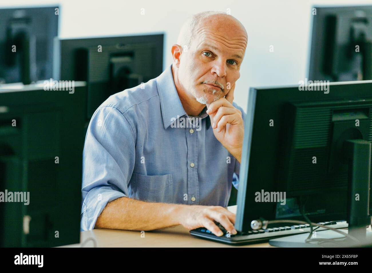 Un professionista esperto si impegna con un computer in una stanza ben illuminata, dimostrando la sua esperienza in un ambiente di ufficio moderno Foto Stock