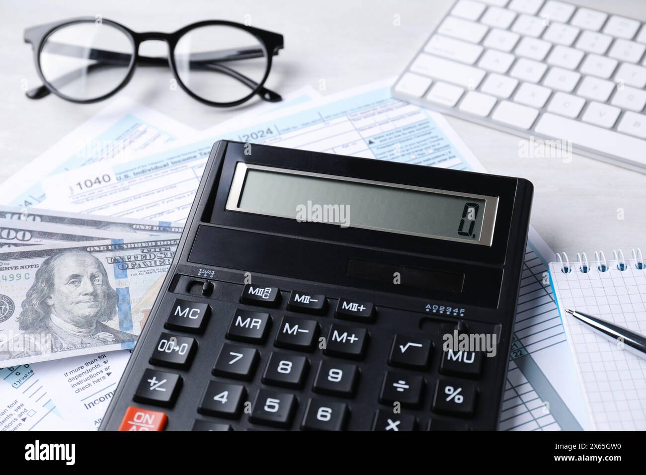 Contabilità fiscale. Calcolatrice, documenti, soldi, cancelleria e bicchieri su tavolo grigio chiaro, primo piano Foto Stock