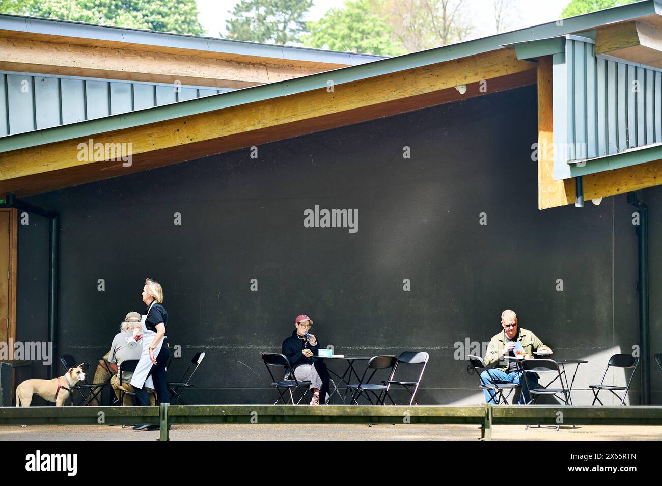 Cameriera che serve i clienti ai tavoli esterni del Pavillion di Avenham Park, Preston, Regno Unito Foto Stock Cameriera che serve i clienti ai tavoli esterni del Pavillion di Avenham Park, Preston, Regno Unito Foto Stock