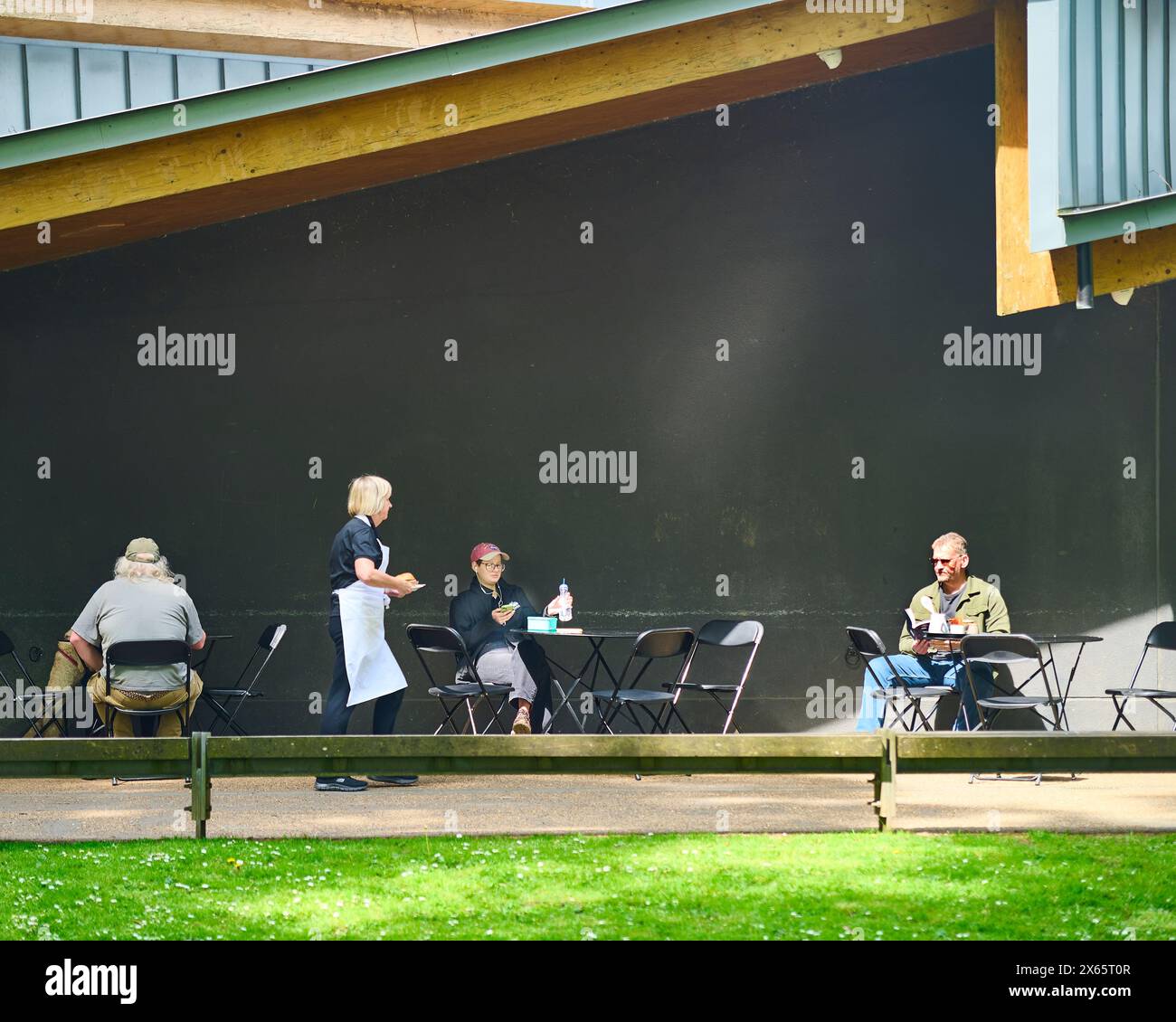 Cameriera che serve i clienti ai tavoli esterni del Pavillion di Avenham Park, Preston, Regno Unito Foto Stock Cameriera che serve i clienti ai tavoli esterni del Pavillion di Avenham Park, Preston, Regno Unito Foto Stock