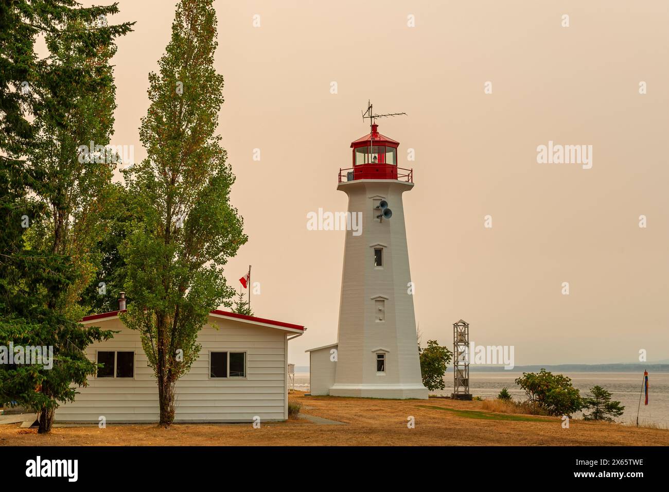 Faro di Cape Mudge con bagliore rosso di incendi boschivi, Quadra Island, British Columbia, Canada. Foto Stock