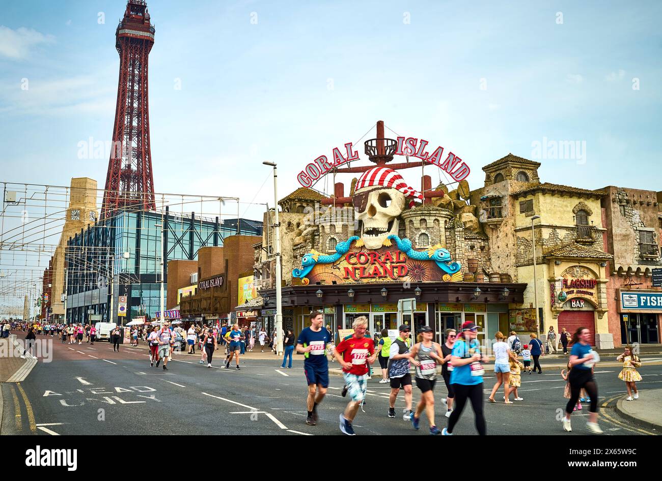 I corridori della corsa di 10 km di Blackpool (2024) passano davanti alla torre e a Coral Island Foto Stock