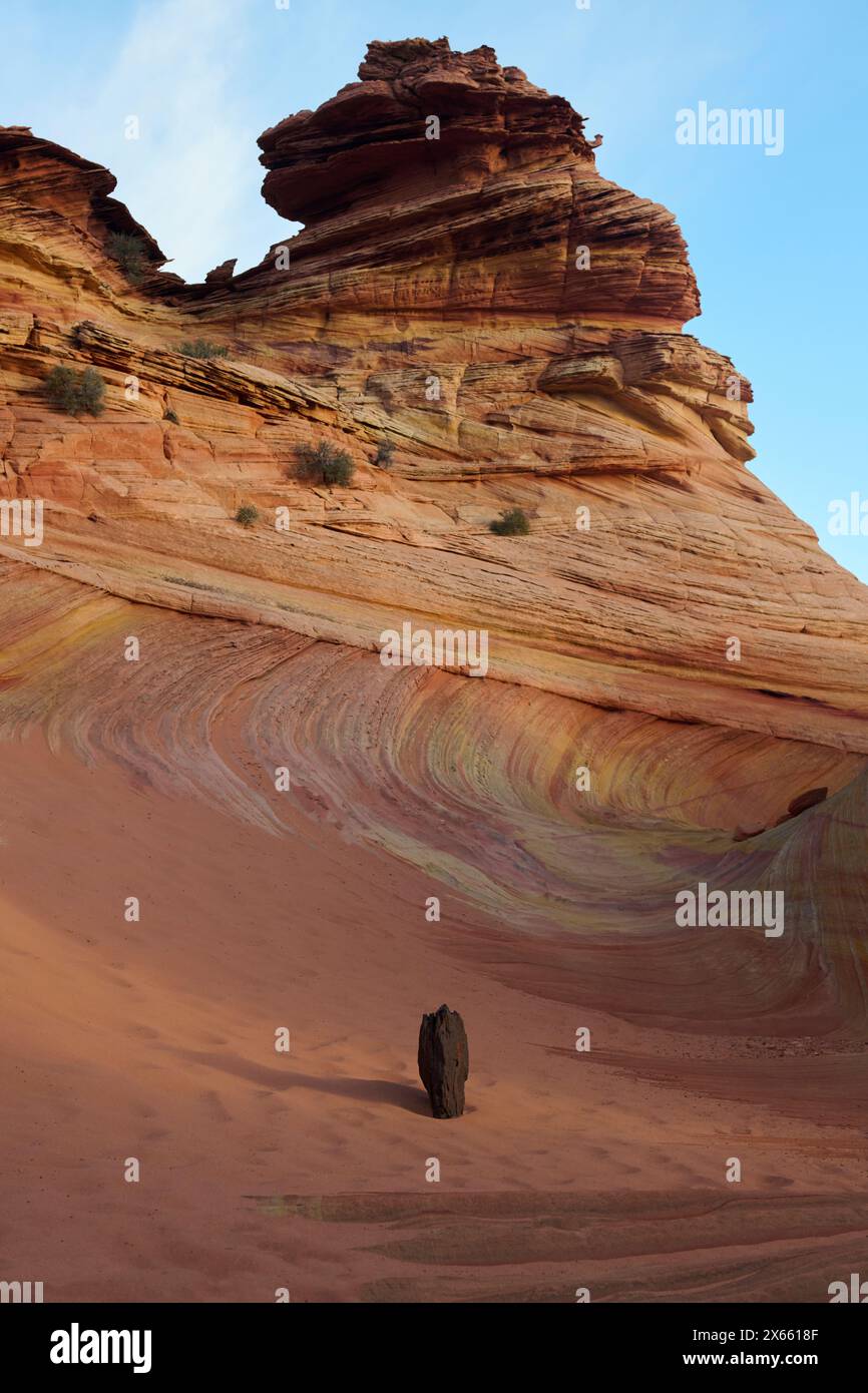 Una roccia solitaria nella sabbia di fronte ad alcune formazioni rocciose selvagge Foto Stock