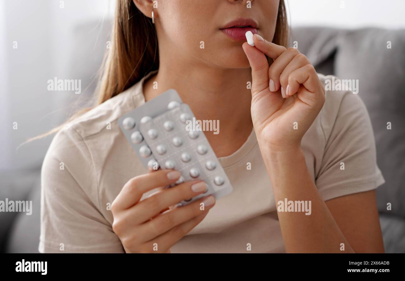 Una donna non identificata prende una pillola e tiene gli altri in mano Foto Stock