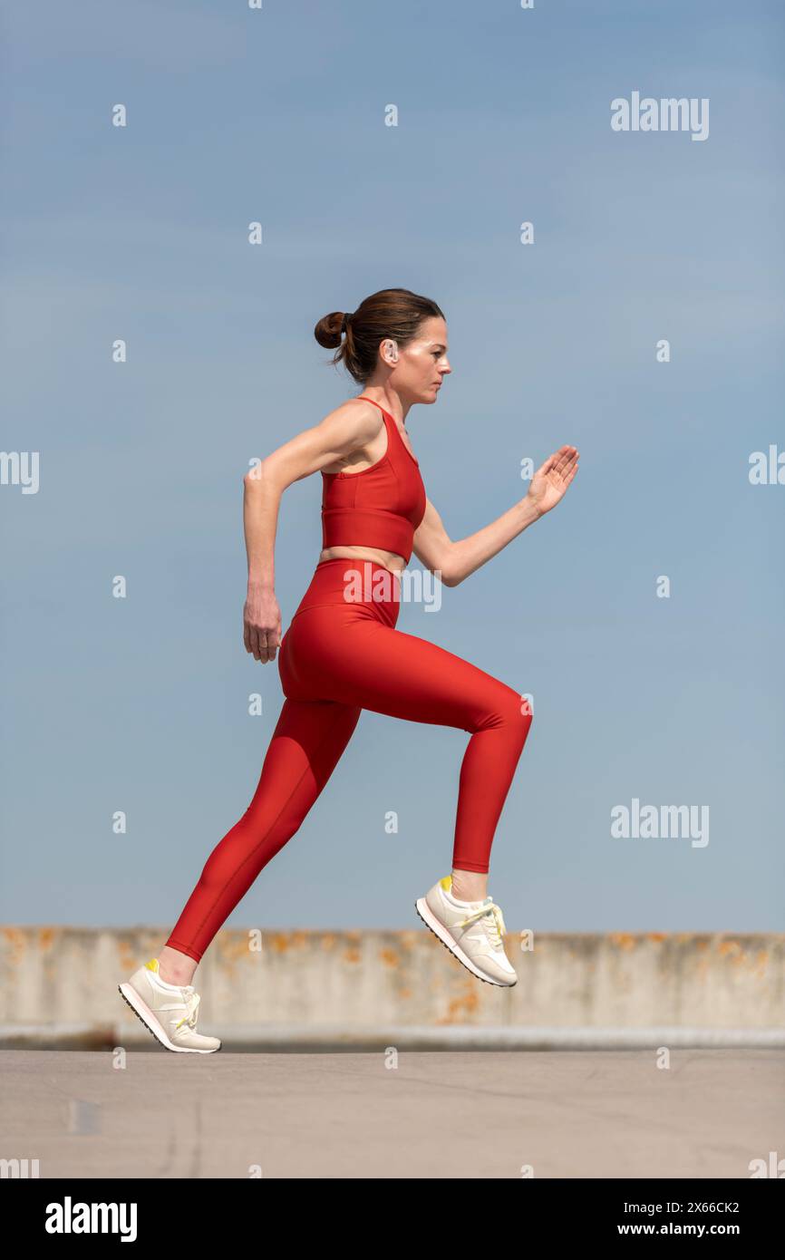 donna adulta che corre e fa jogging all'aperto, sfondo blu Foto Stock