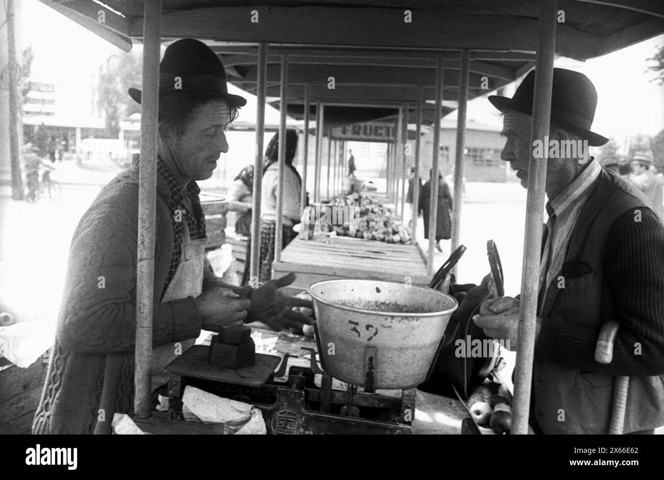 Repubblica Socialista di Romania negli anni '1970 Venditore e acquirente in un mercato agricolo in una piccola città. Foto Stock
