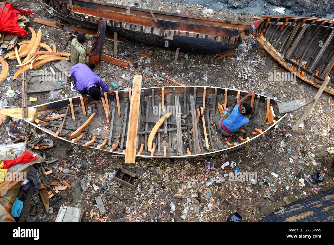 Dacca, Bangladesh. 13 maggio 2024. I lavoratori stanno costruendo piccole imbarcazioni di legno per il trasporto passeggeri sulle rive del fiume Buriganga a Keraniganj, Dacca. Queste piccole barche sono l'unico mezzo per attraversare il fiume. Sulla barca possono sedersi un massimo di 6 persone. (Immagine di credito: © Syed Mahabubul Kader/ZUMA Press Wire) SOLO PER USO EDITORIALE! Non per USO commerciale! Foto Stock