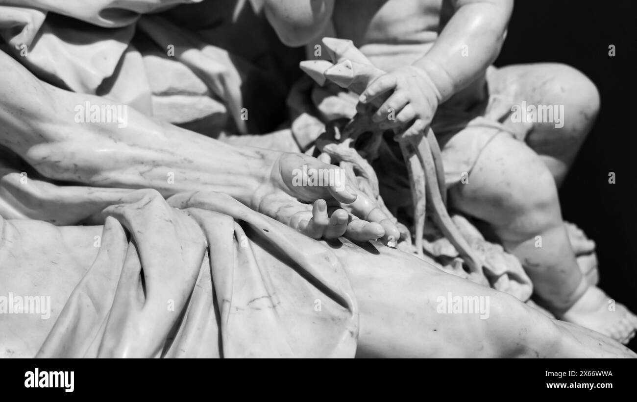 Foto in bianco e nero che mostra in dettaglio sculture in pietra che rappresentano un mucchio di unghie piegate tenute dalla mano di un bambino accanto al corpo morto di Gesù Foto Stock