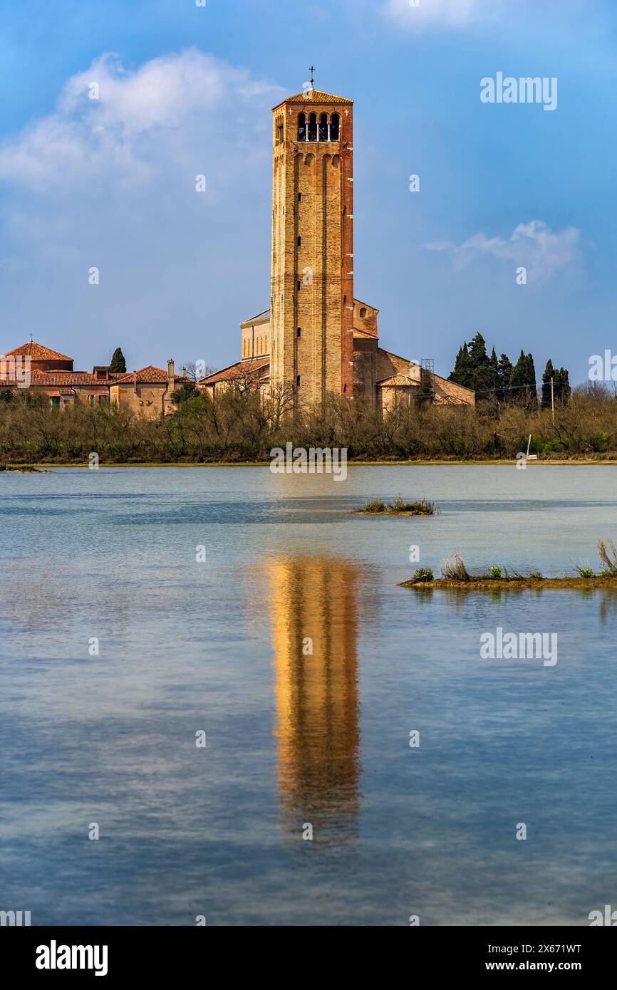 Basilica di Santa Maria Assunta sull'isola di Torcello nella laguna di Venezia, Italia. Campanile della chiesa risalente all'XI secolo con riflessi a specchio in wa Foto Stock