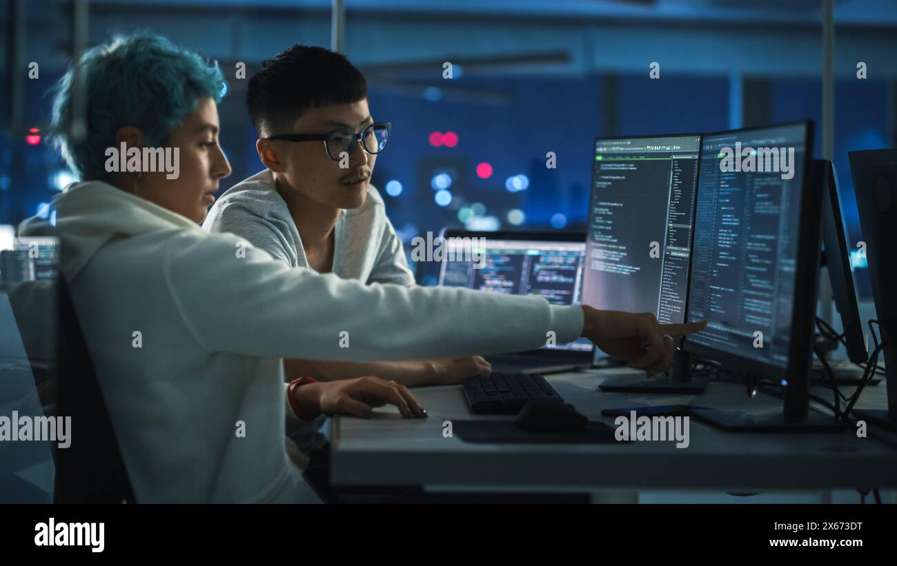 Lavoro di squadra in diversi uffici notturni: Il project manager parla con Creative Solutions Specialist e parla di computer con codice app. Giovani professionisti programmazione, creazione di software e-Commerce Foto Stock