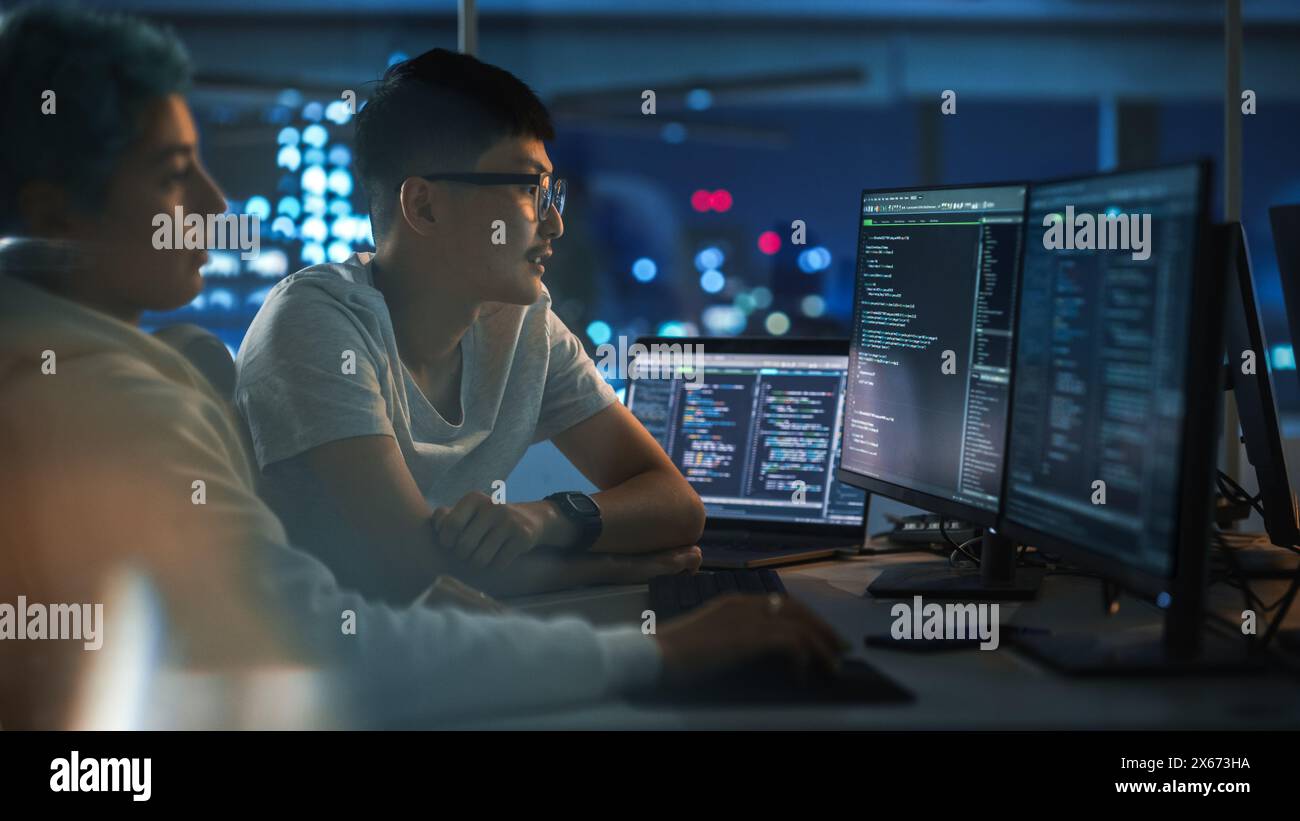 Lavoro di squadra in diversi uffici notturni: Il project manager parla con Creative Solutions Specialist e parla di computer con codice app. Giovani professionisti programmazione, creazione di software e-Commerce Foto Stock