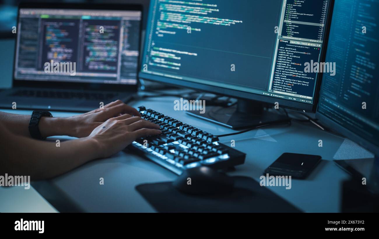 Primo piano concentrati sulle mani della persona che digita sulla tastiera illuminata del computer desktop. Le schermate mostrano l'interfaccia utente del linguaggio di codifica. Software Engineer Crea un'innovativa app per il commercio. Sviluppo del programma Foto Stock