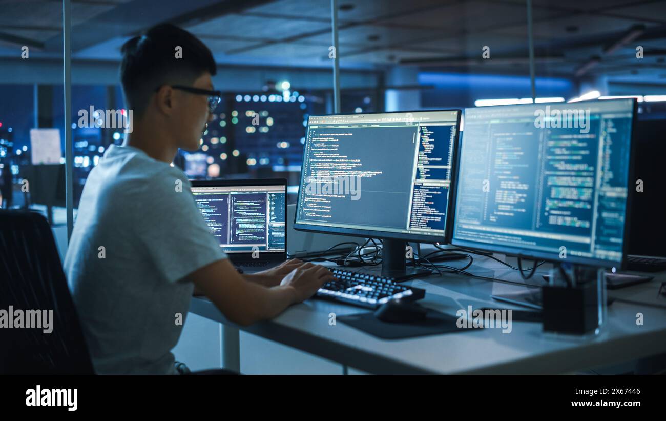 Ufficio notturno: Giovane giapponese che lavora su un computer desktop. Digital Entrepreneur Typing Code, Creating Modern software, e-Commerce App Design, e-Business Programming. Sulla spalla Foto Stock
