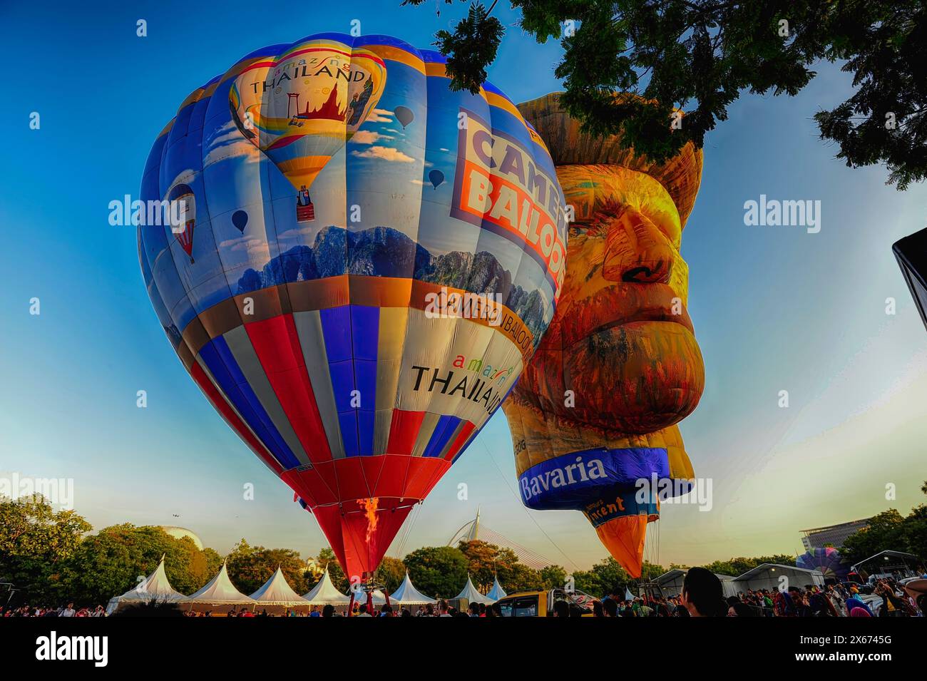 Due mongolfiere fluttuano nel cielo, una delle quali ha la forma di un volto umano. L'altro pallone ha la forma di un orso gigante. La scena è li Foto Stock