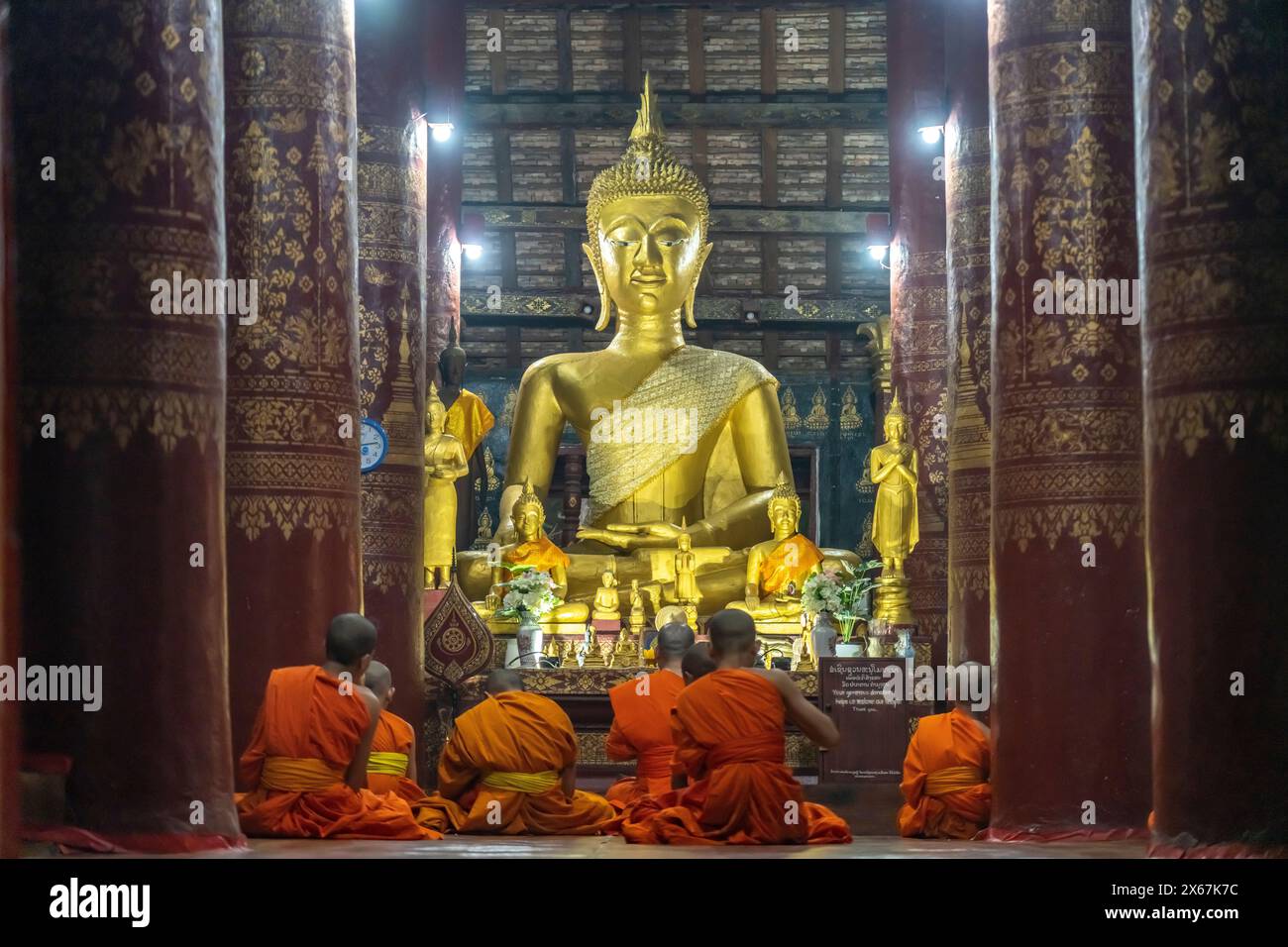 Monaci che pregano di fronte al grande Buddha nel tempio Wat Pak Khan Khammungkhun, Luang Prabang, Laos, Asia Foto Stock