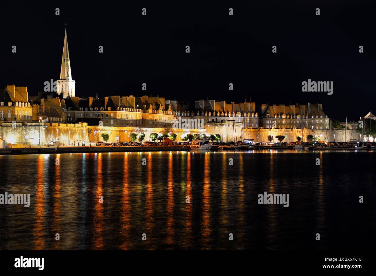 Vista notturna di Saint Malo, Bretagna - Francia. Luci riflesse nell'acqua di ondulazione. Foto Stock