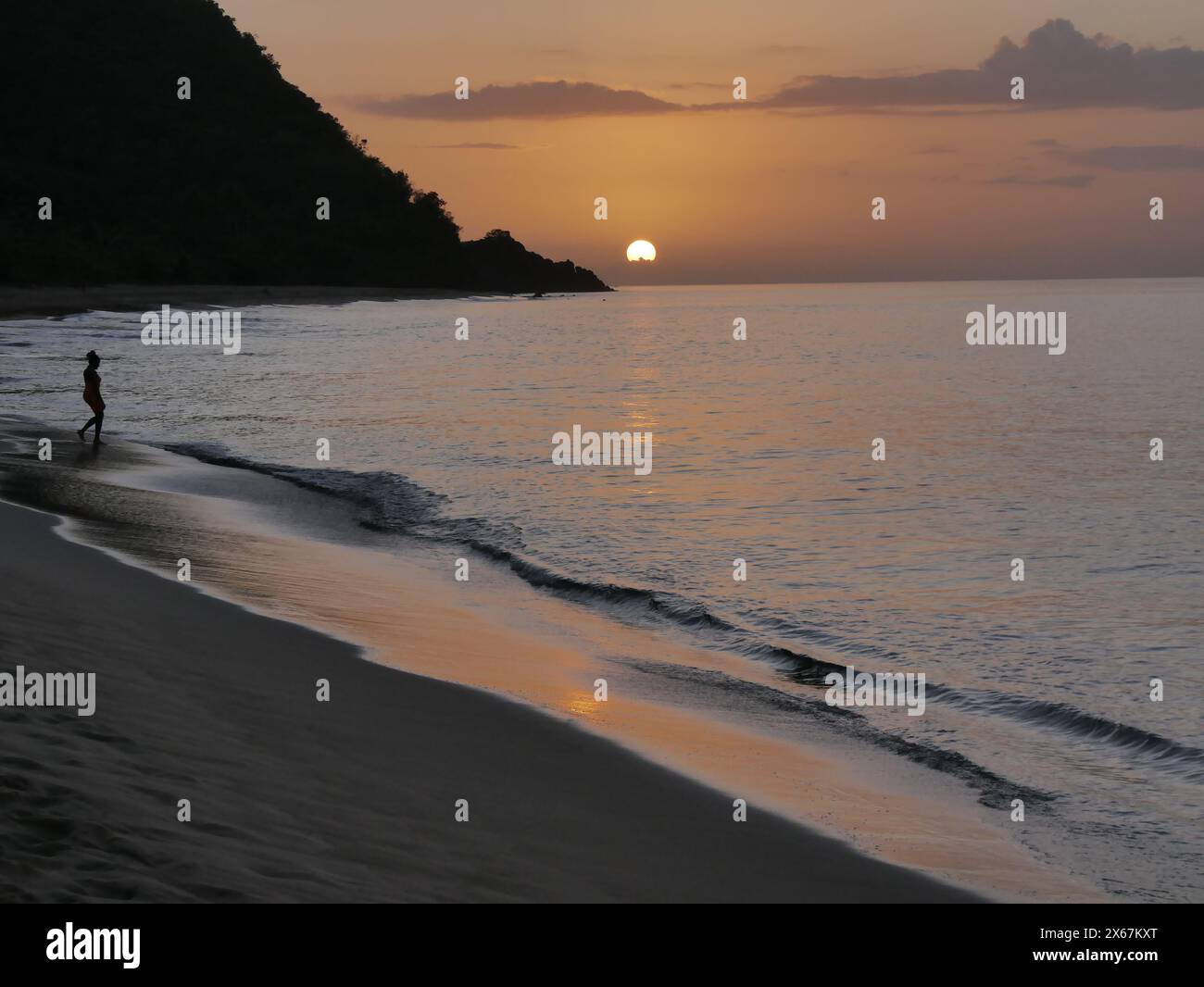 silhouette di una donna sulla spiaggia di grande anse al tramonto, deshaies, guadalupa Foto Stock