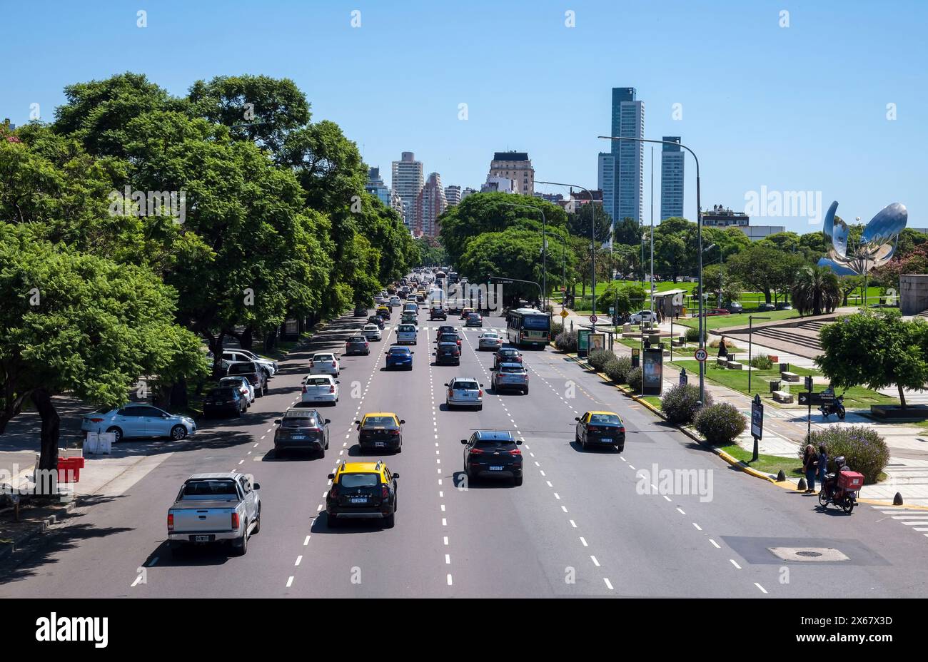 Buenos Aires, Argentina, traffico cittadino su Av. Pres. Figueroa Alcorta, strada a senso unico con 6 corsie nel quartiere cittadino di Recoleta. Sulla destra del parco si trova l'attrazione Floralis generica. Floralis generica è una scultura realizzata in acciaio e alluminio nella Plaza de las Naciones Unidas, Avenida Figueroa Alcorta, Buenos Aires, un dono alla città dell'architetto argentino Eduardo Catalano. Foto Stock