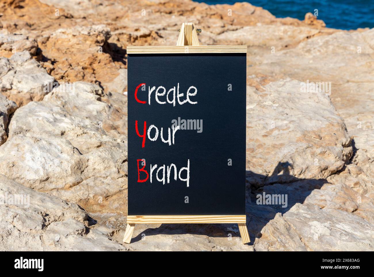 CYB Crea il simbolo del tuo marchio. Parole concettuali CYB Crea il tuo marchio su una bellissima lavagna gialla. Bellissimo sfondo blu cielo in pietra. Business CY Foto Stock