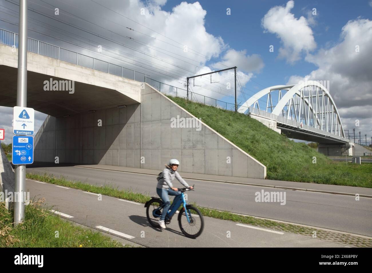 Ciclista che utilizza la pista ciclabile che passa sotto il ponte ferroviario sul canale Albert vicino a Hasselt, Belgio. Foto Stock