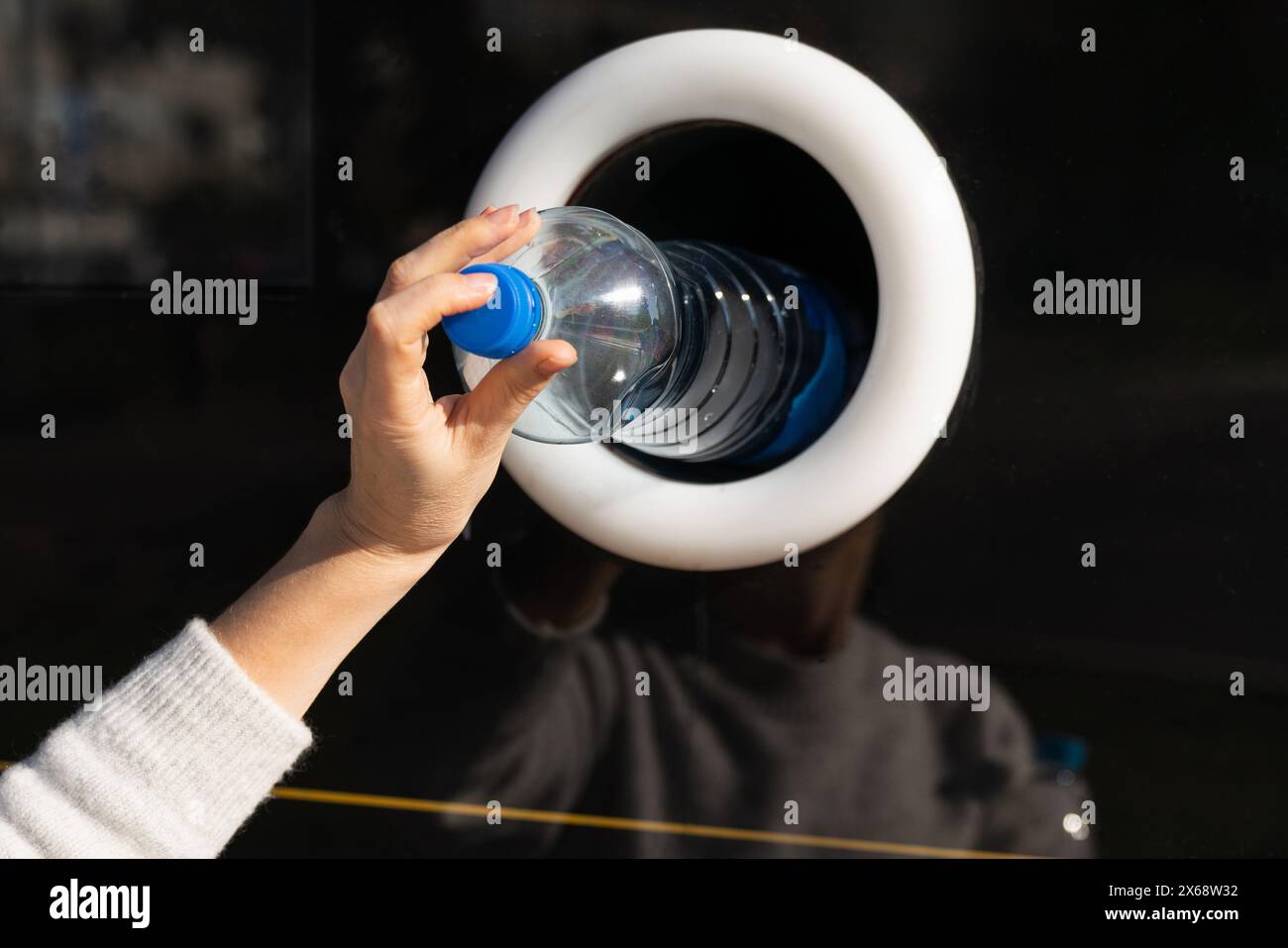 La donna usa una macchina self-service per ricevere bottiglie e lattine di plastica usate in una strada cittadina. Foto Stock