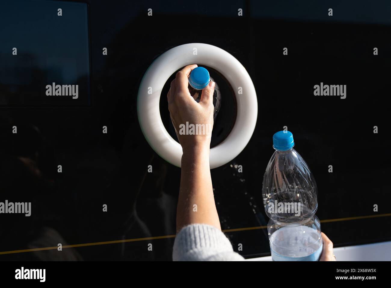 La donna usa una macchina self-service per ricevere bottiglie e lattine di plastica usate in una strada cittadina. Foto Stock