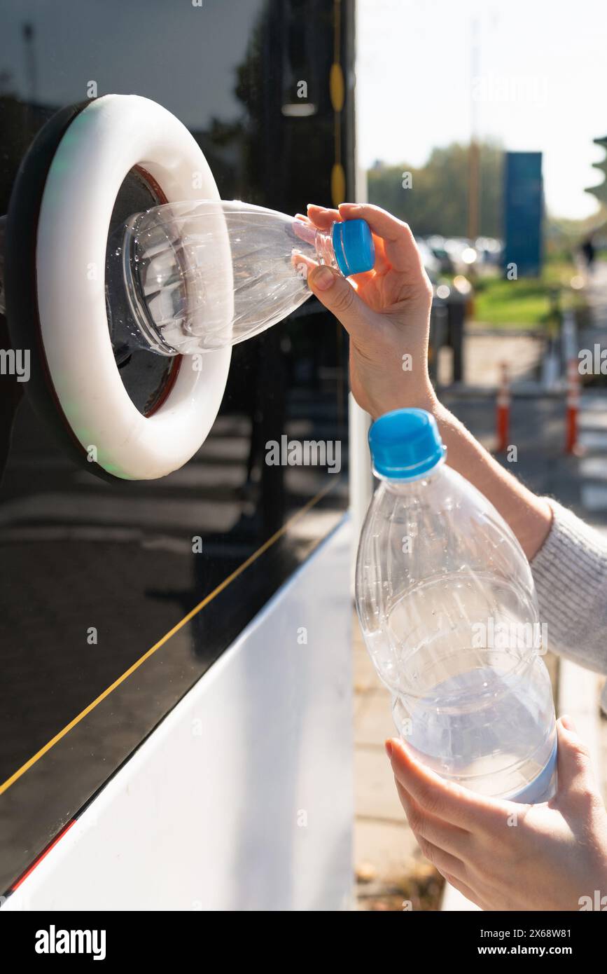 La donna usa una macchina self-service per ricevere bottiglie e lattine di plastica usate in una strada cittadina. Foto Stock