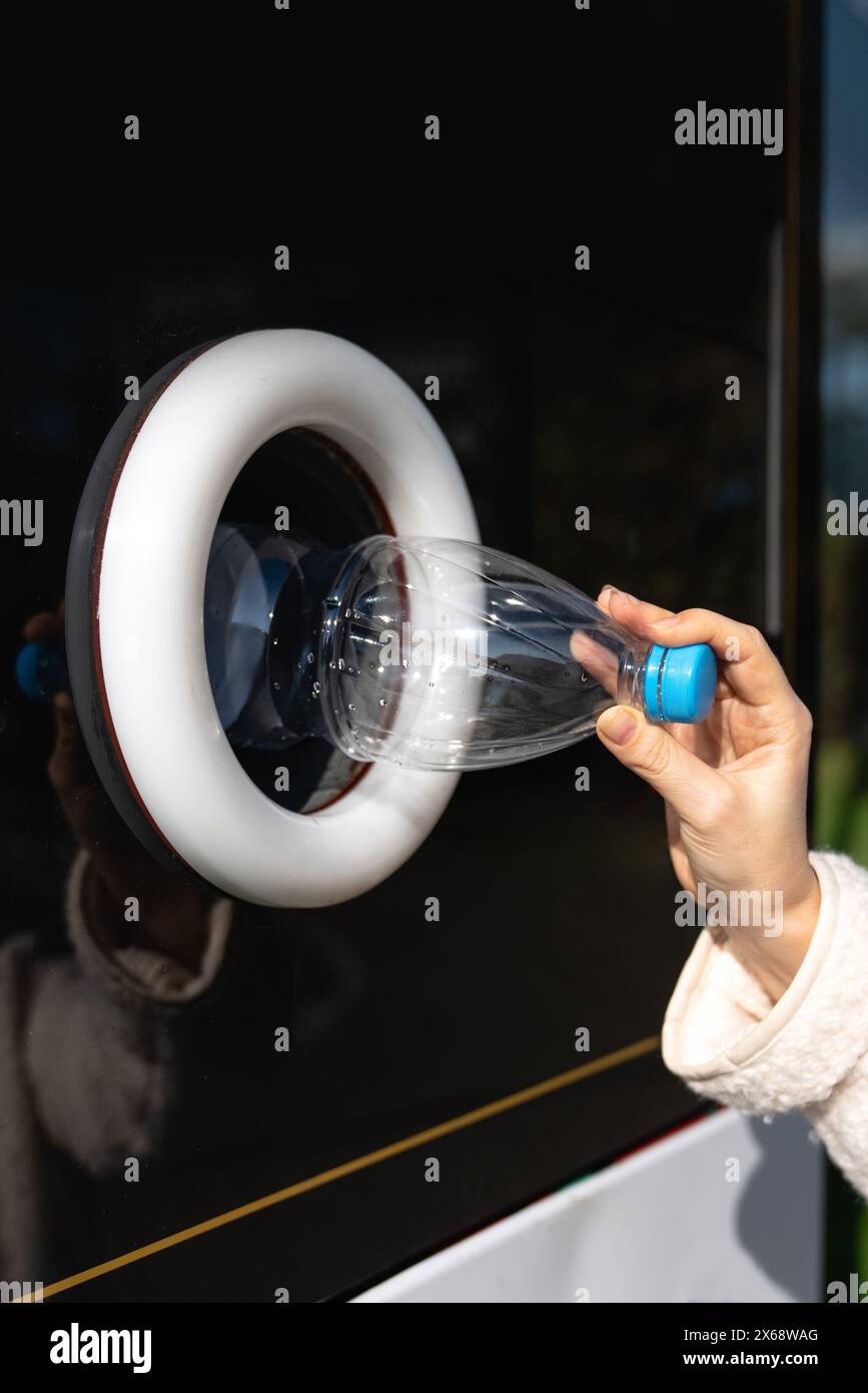 La donna usa una macchina self-service per ricevere bottiglie e lattine di plastica usate in una strada cittadina. Foto Stock