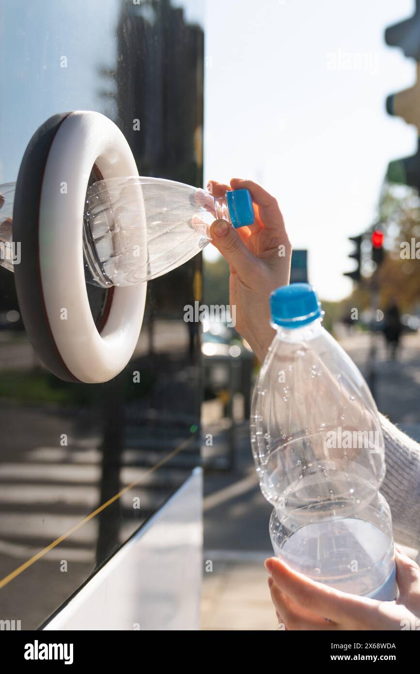 La donna usa una macchina self-service per ricevere bottiglie e lattine di plastica usate in una strada cittadina. Foto Stock