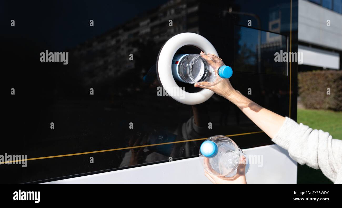 La donna usa una macchina self-service per ricevere bottiglie e lattine di plastica usate in una strada cittadina. Foto Stock