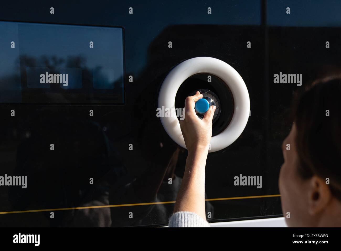 La donna usa una macchina self-service per ricevere bottiglie e lattine di plastica usate in una strada cittadina. Foto Stock