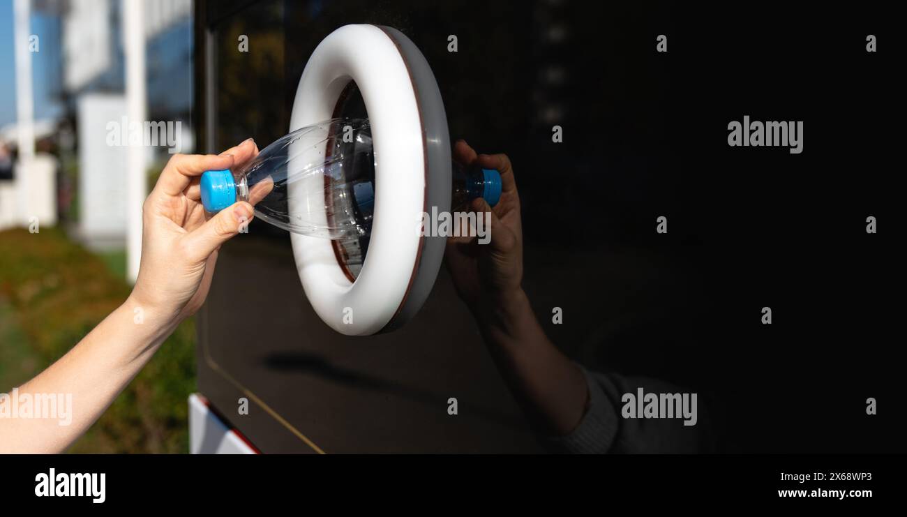 La donna usa una macchina self-service per ricevere bottiglie e lattine di plastica usate in una strada cittadina. Foto Stock