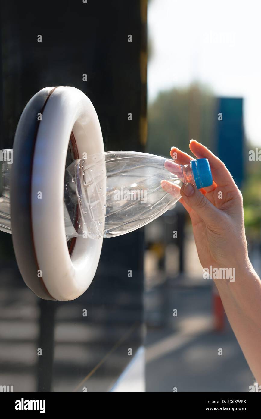 La donna usa una macchina self-service per ricevere bottiglie e lattine di plastica usate in una strada cittadina. Foto Stock