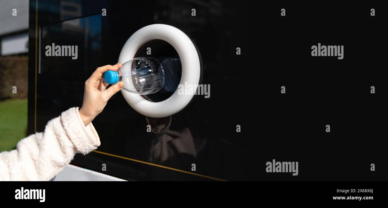 La donna usa una macchina self-service per ricevere bottiglie e lattine di plastica usate in una strada cittadina. Foto Stock