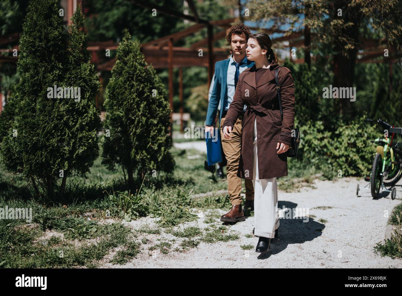 I professionisti che viaggiano per affari camminano in un parco lussureggiante durante una pausa di lavoro Foto Stock
